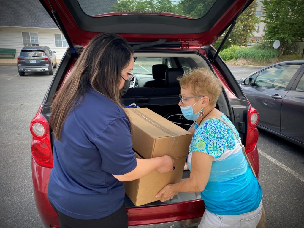 An ACTS staffer assists a client with loading a box of food into her car.